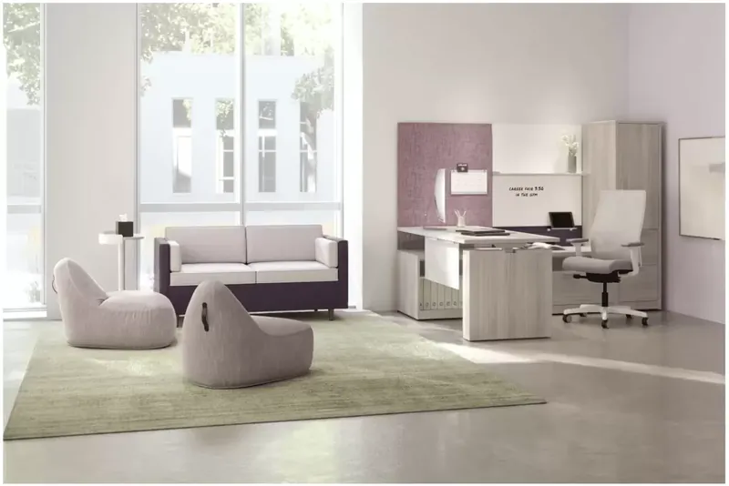 Bright private office with a desk, storage cabinets and lounge seating beside tall windows.